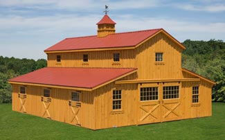 Large two story horse barn with red metal roof and weathervance